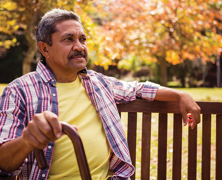 Uplifted Grief - man holding cane sitting on park bench